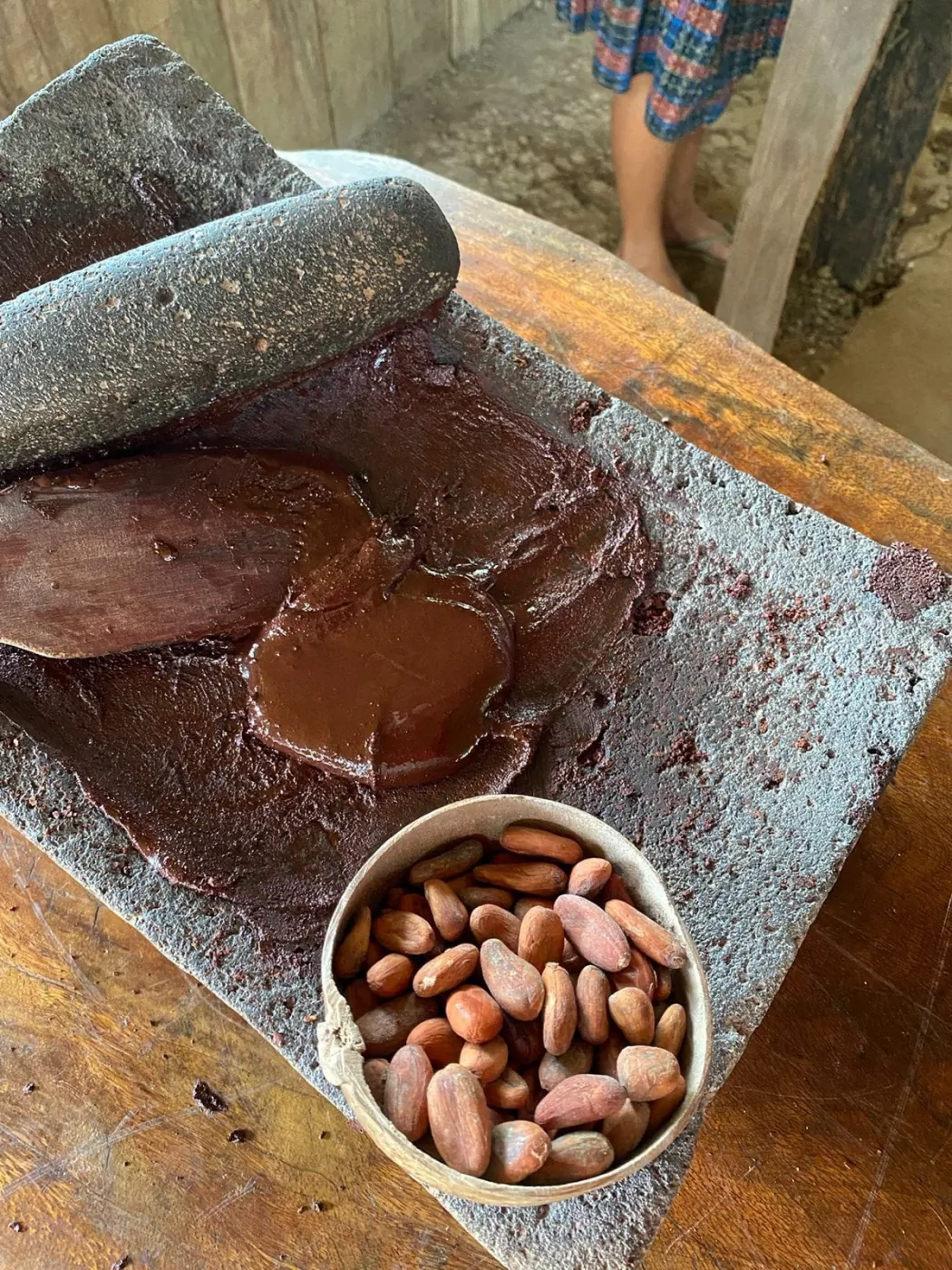 Fresh cacao paste and beans on a traditional grinding stone