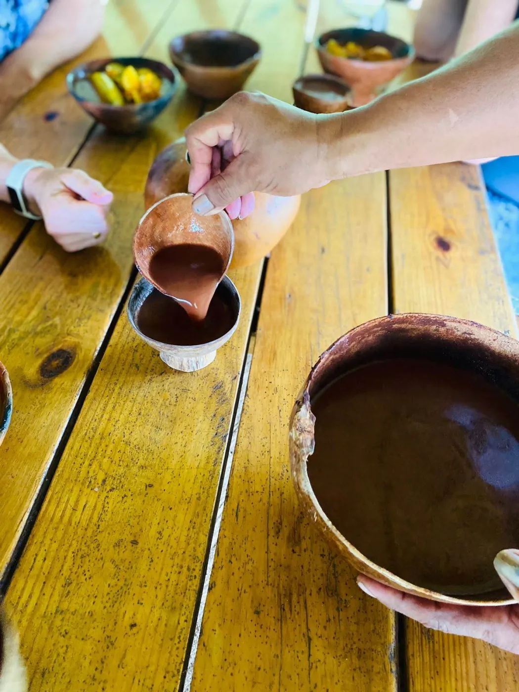 A traditional cacao drink being poured from a gourd bowl