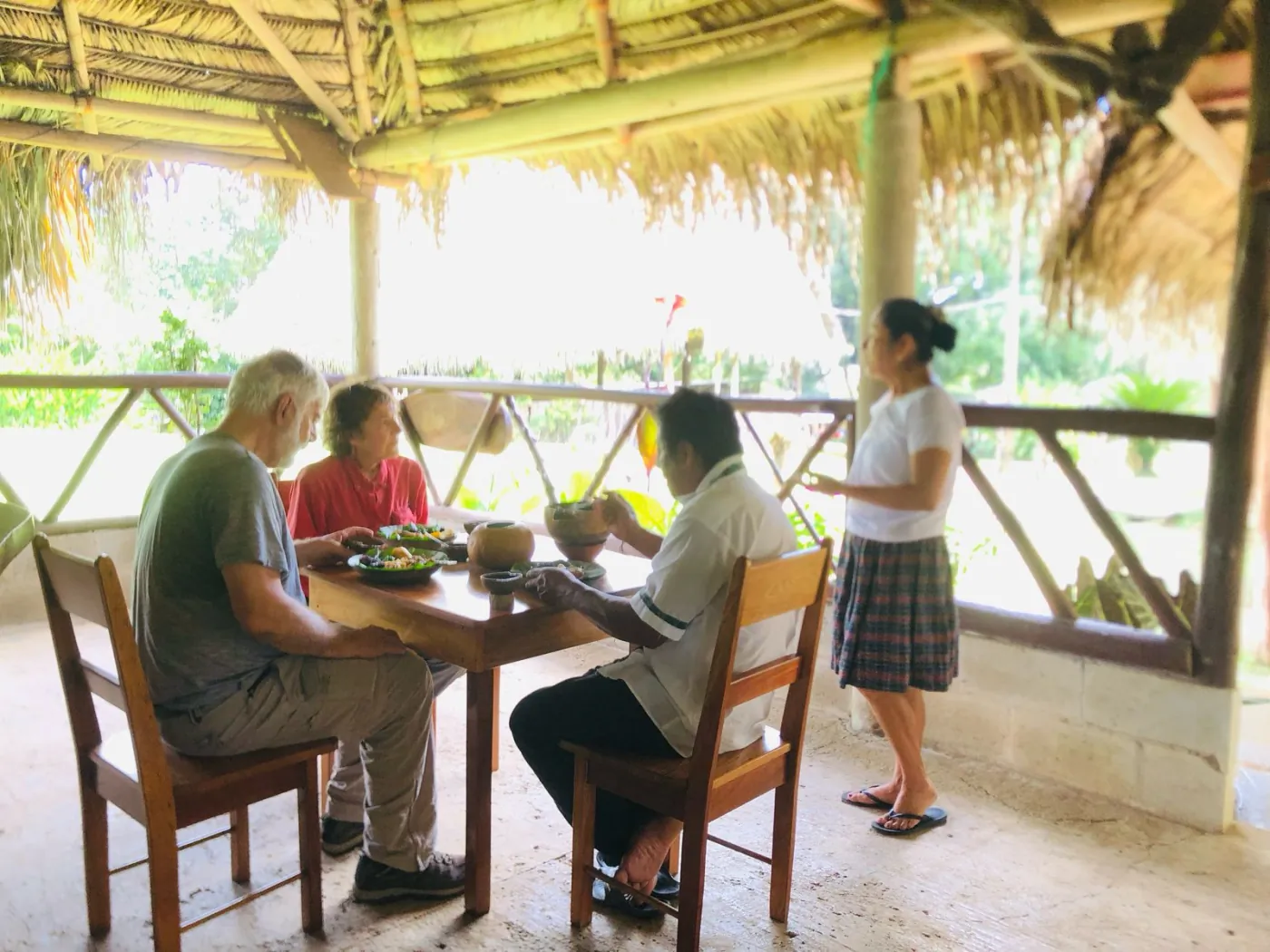 Guests and local Maya hosts sharing a meal in the open-air dining space